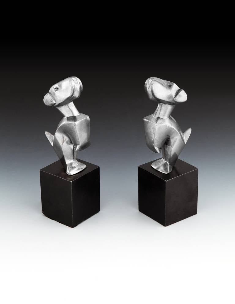 A superb pair of humorous silvered bronze modernist styled terriers, most likely intended as bookends or car mascots, with forelegs raised in a begging stance, mounted on their original cubed, black marble bases.