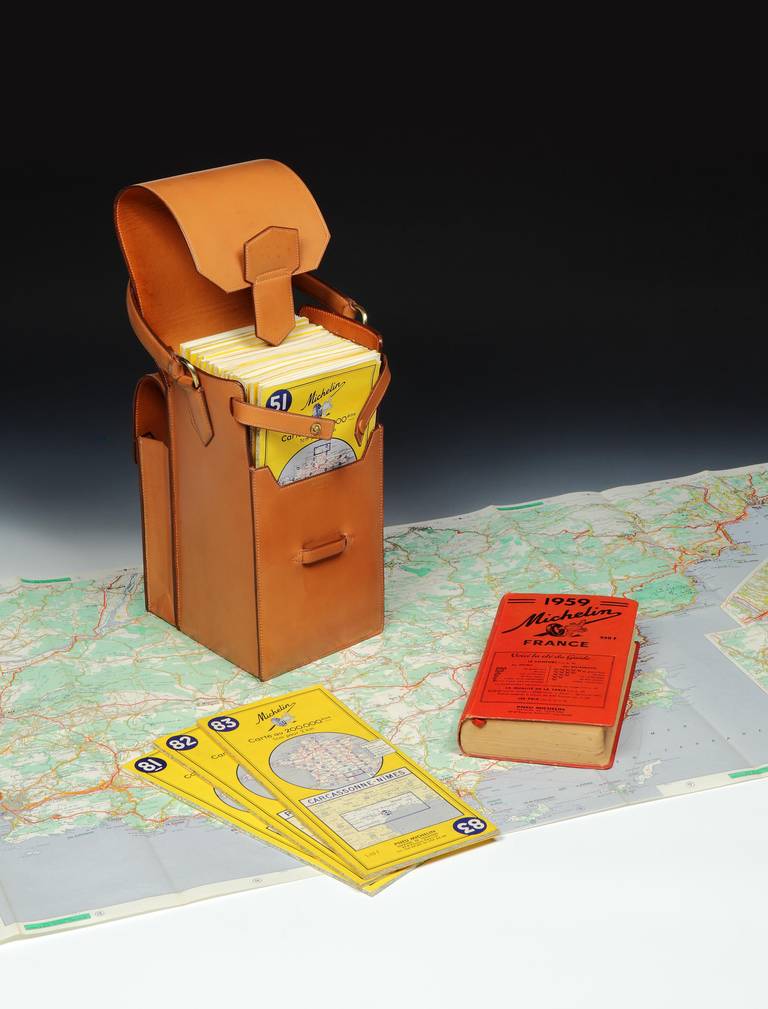 A seemingly unused (and most likely unique special order) travelling map case by Hermès, in light-colored pigskin with a looped handle, with one larger compartment secured with a tab and containing 37 individual, fold-out Michelin road maps of