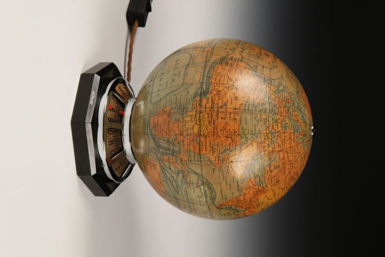 A terrestrial globe timepiece with coloured printed gores, by J. Forest, of Paris, rotating via a barrel movement and raised on a chromed frame bordering the annular dial, the whole mounted on a signed octagonal slate base. 

Note: this piece has