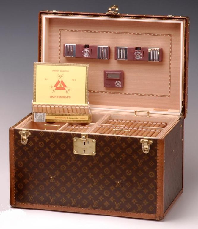 A magnificent ‘malle cigares’ of unusually large proportions, the interior re-fitted in seasoned Spanish cedar with removable trays and quadruple humidifiers. Storage of up to 600 cigars, the exterior with brass binding and leather handle to lid.