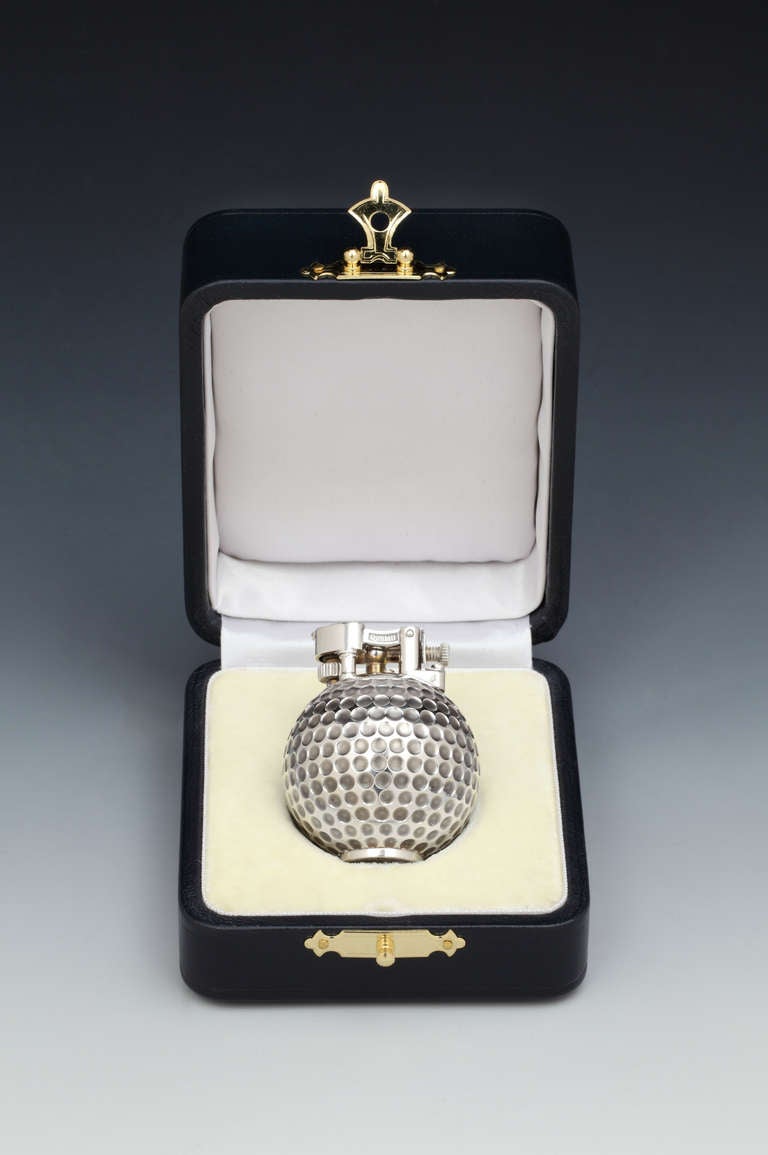 An extraordinary and very rare Sterling silver 'Unique' table cigarette lighter, modelled as a golf ball, almost life size in scale, the lift-arm signed Dunhill, and the bottom edge hallmarked London, 1973.

In a bespoke, calfskin Dunhill