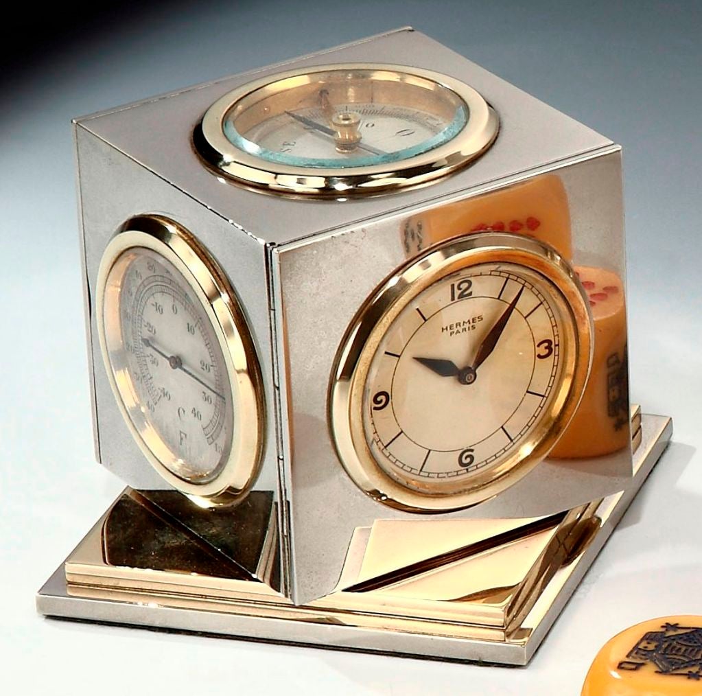 A rare ‘Cube’ desk clock/weather-station, comprising clock, thermometer, barometer, perpetual calendar and compass, the nickel-plated rotating body on stepped plinth. Signed Hermès Paris, French.