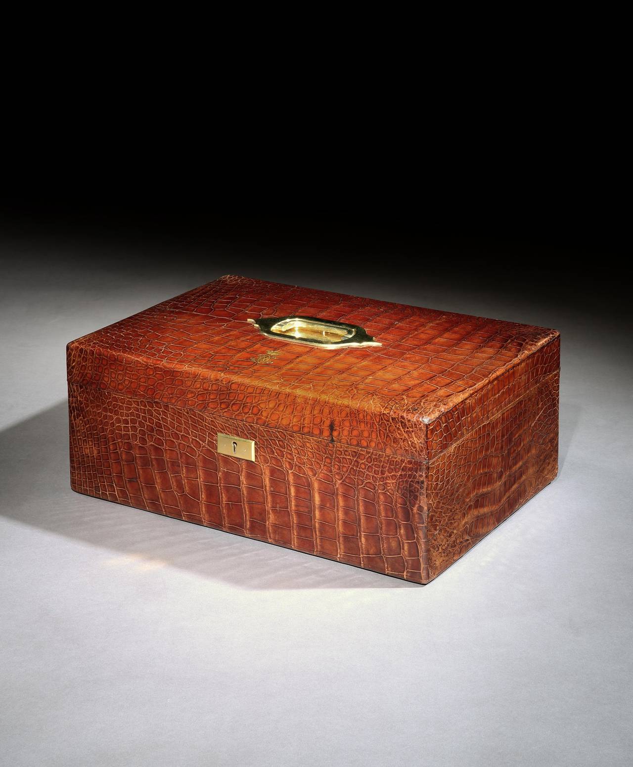 A time warp piece in the form of a Victorian crocodile-hide dispatch box or case, the top of the box with a recessed brass handle and embossed monogram with crown, the Chubb patented lock with original key present. The interior also lined with