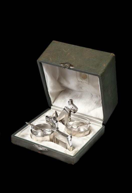 A pair of Art Deco ‘salts’ by Orfévrerie Gallia, France. The main bodies in silvered bronze, the liners in clear glass, the spoons in silver, with marks of GALLIA to the base on one of the frames, the pair in their original Gallia box with stamped