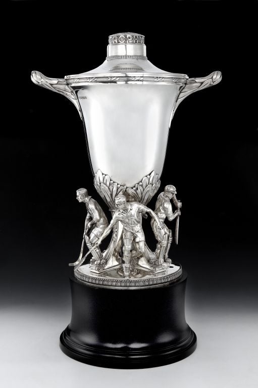 A monumental Sterling silver, early Elizabeth II trophy cup, with a domed circular cover with raised centre chased with fruiting laurel above an applied cut-card inscription and a band of lotus, laurel wrapped reeded rim and handles, the campana
