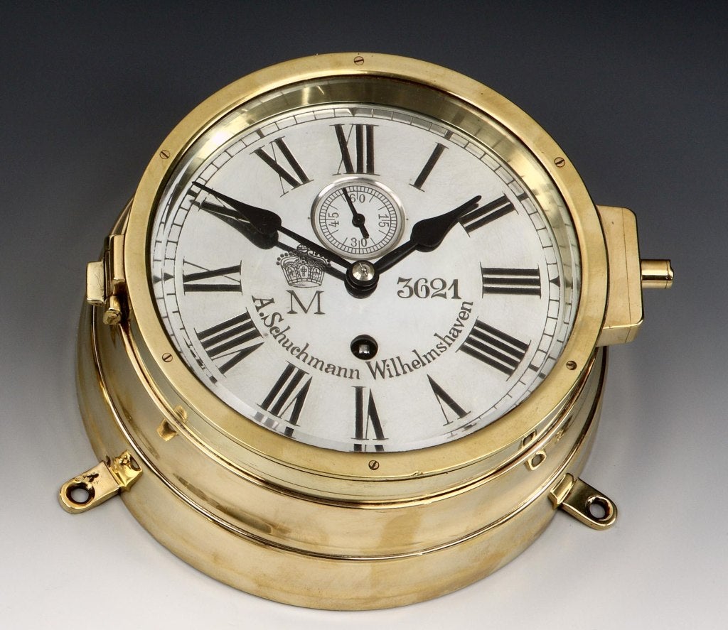 A brass Zeppelin airship’s bulkhead clock with original polished silvered dial with crowned ‘M’ applied, and number 3621, with secondary dial and maker’s marks A. Schuchmann Wilhelmshaven to the face. Engraved to the top of the casing, the Airship