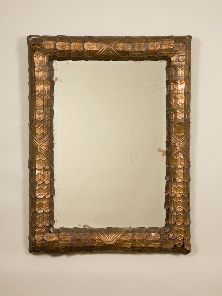 A 1940's French rectangular mirror, the frame decorated with overlapping stylized copper leaves.