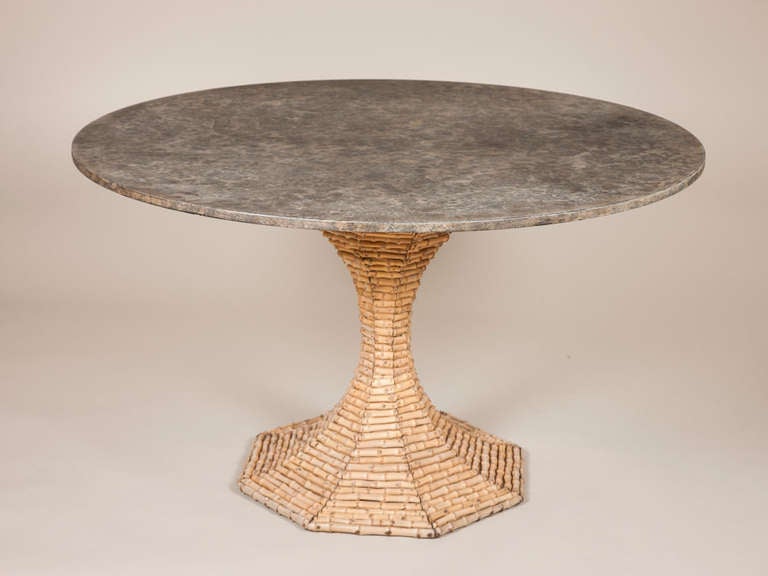 A 1950s circular table with a faux marble top and a bamboo lined waisted base.