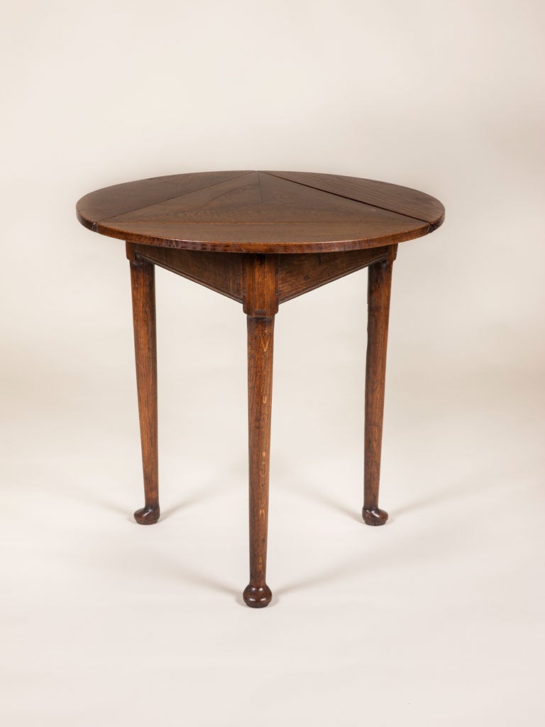 A George III oak circular handkerchief table with three drop leafs and legs with paw feet.