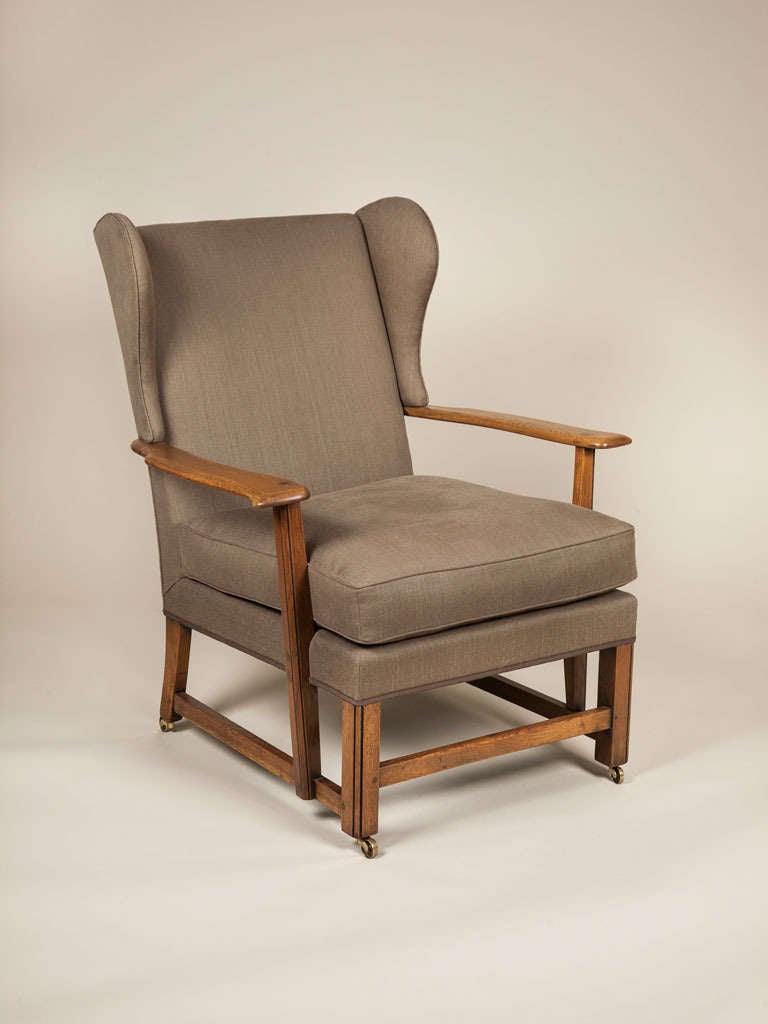 A pair of 1930s oak framed Cotswold School wing armchairs with open arms and padded backs and seats.