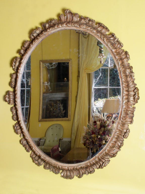 A large 18th century Italian oval mirror with a spectacular acanthus carved, painted and gilded frame.