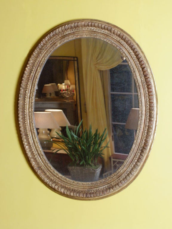 A large 17th century Italian oval mirror with a finely carved and gilded frame and a later plate.