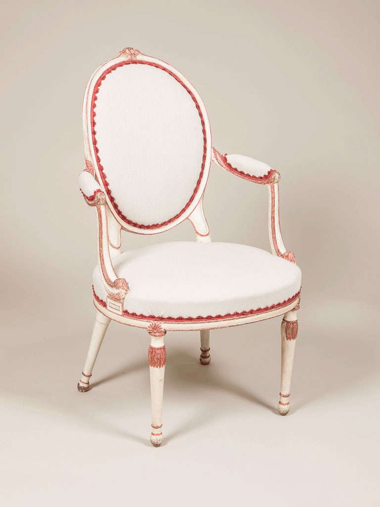 A late 18th century English painted elbow chair with an oval back and carved decoration, in the manner of Hepplewhite.