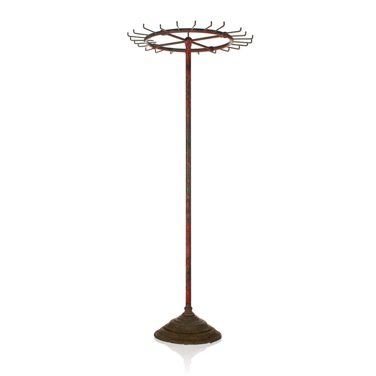 This antique round rack with its industrial machine age look, may have been used in a store for coats or belts. It stands 48