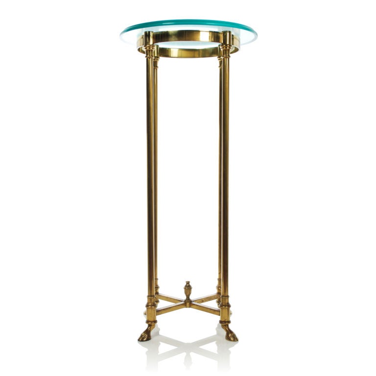 LaBarge brass and glass pedestal with finial topped X stretcher and hoof feet. The beauty and quality of this piece shows in every detail. Made in Italy, the base has a solid brass X stretcher and is very sturdy. The thick glass top has an ogee