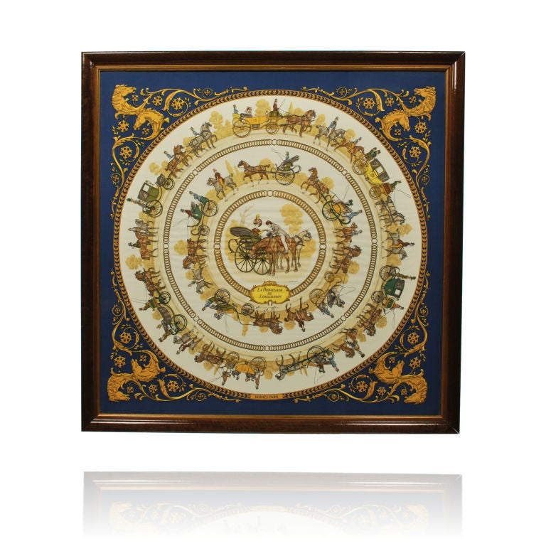 This is a splendid vintage silk scarf by Hermes of Paris. The navy blue and gold scarf depicts horse drawn carriages encircled in gold chains.
