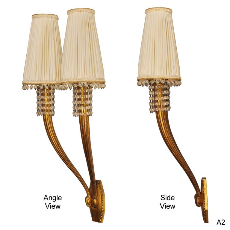 This is an elegant pair of twin arm wall sconces by Jacques-Emile Ruhlmann. The large fluted arms with their sinuous curves, are enhanced by the elegant strands of crystal pearls. Ruhlmann called these his Antilope (Antelope) wall lights.

This
