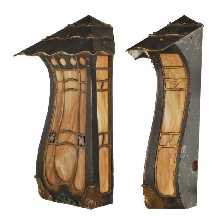 Splendid pair of early 1900's cast bronze wall sconces with Gothic style ornamental decorations and colorful slag glass panels. This handsome pair of light sconces are very well made and have wonderful details, right down to the pair of birds on