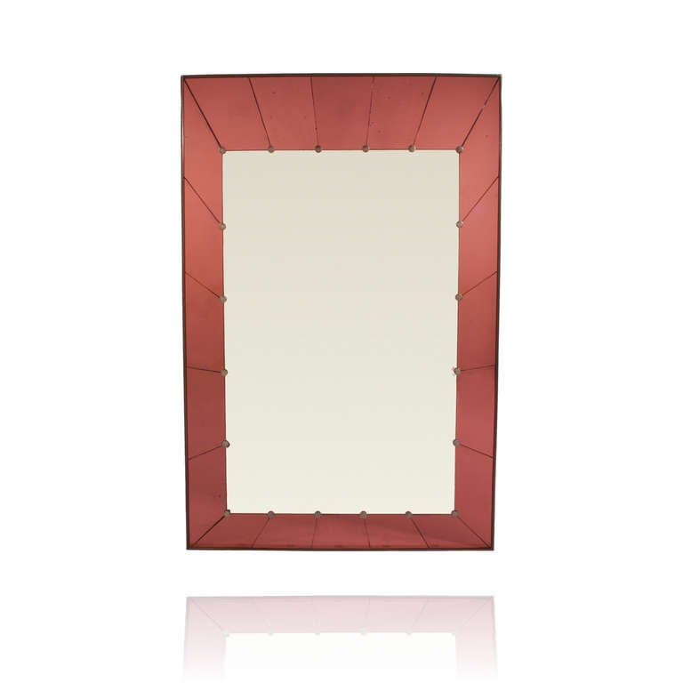 This fabulous Murano mirror is attributed to Cristal Arte, and has a gorgeous Tuscan red or rosso mirror frame border. The segmented mirror border has a silvered brass button where each joint meets the central mirror plate. Its large scale size