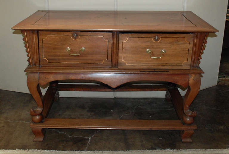 A Philippine Tindalo wood mesa altar table with a five-piece floating panel top and tapered beaded edge. Two large drawers with wood inlay and brass handles, Cabriole and ball legs standing on well supported cross stretchers. From the ex-Batangas