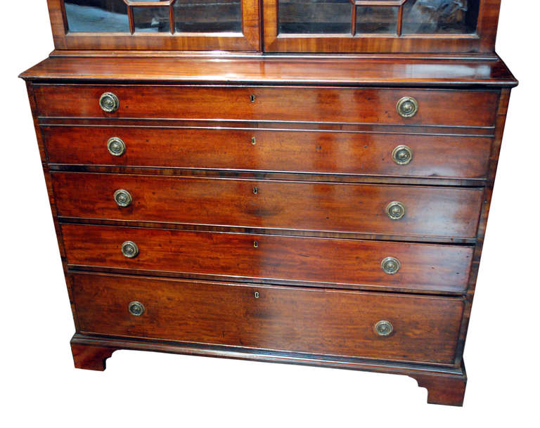 English Mahogany Secretary from George III, Circa 1810. Top drawer's front panel unlocked by key to recline and become a desk. Three shelf glass cabinet, three bottom drawers and eight small drawers inside of secretary desk. Bronze ring shaped