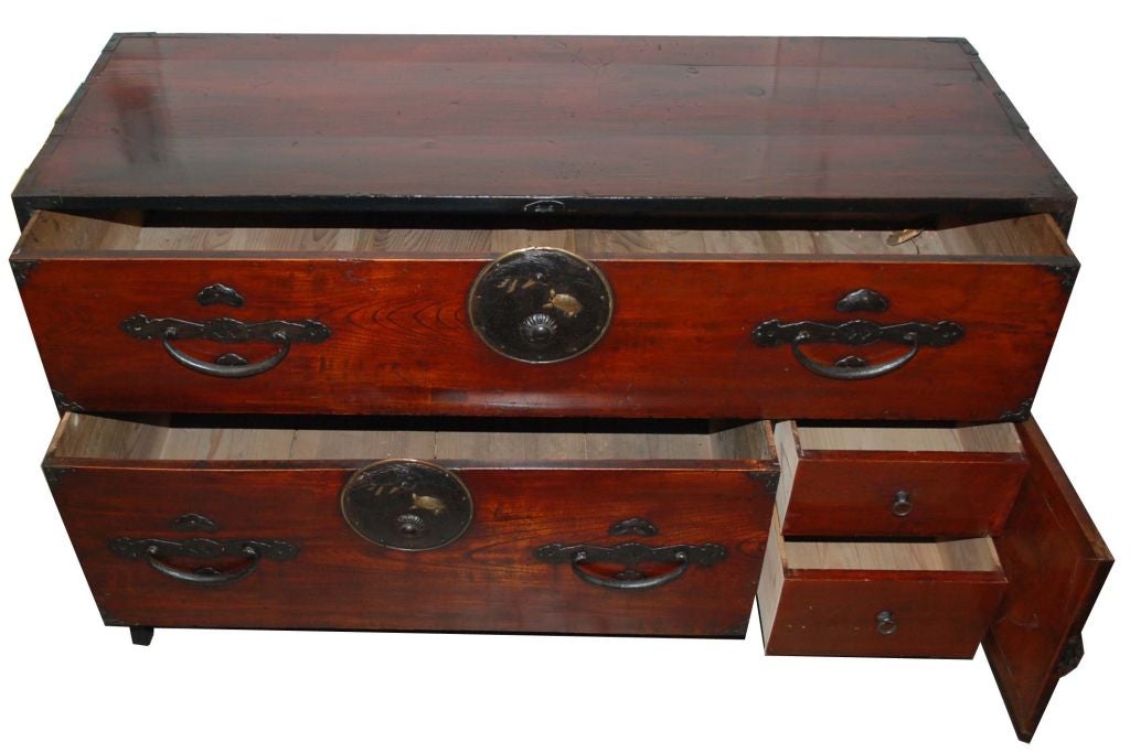 Japanese low tansu with original hardware, one long drawer above one short drawer and one locking door enclosing two drawers. Sitting on iron stand.