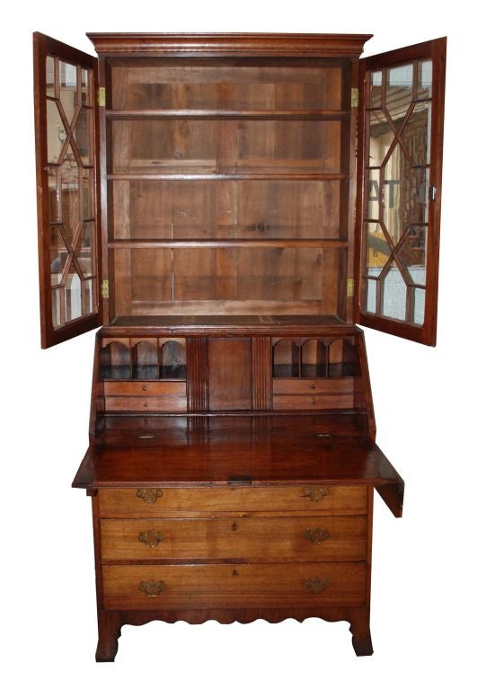 American Federal period secretary desk, with three adjustable shelves behind two paned “thirteen states” tracery cupboard doors, below a cavetto-molded flat cornice molding. Lower section with a drop front enclosing six pigeon holes above four long