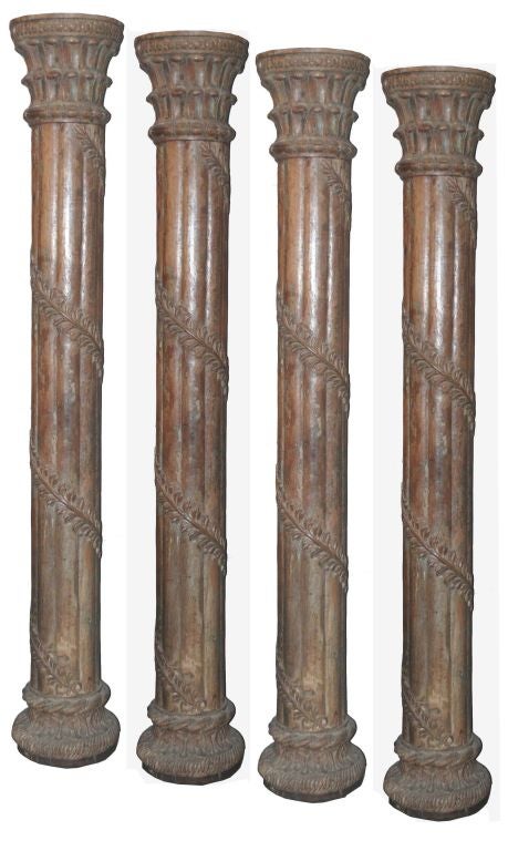 A set of four carved Indian pillars, each with a base and crown.