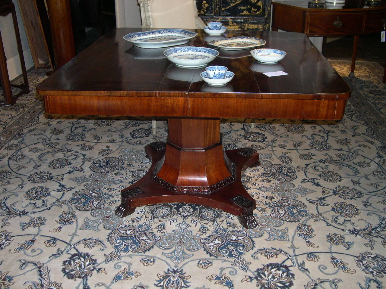 Baltic dining table, a squared top with rounded corners above an tapered octagon pedestal with carved trim, a quadripartite base on four carved lions paw feet, table extends with three leaves.
Mahogany. Excellent antique condition,