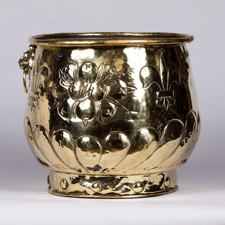 An 18th century brass cache pot from the Louis XIV period. The piece has coat of arms escutcheon, fleur de lys and lion head handle motifs.