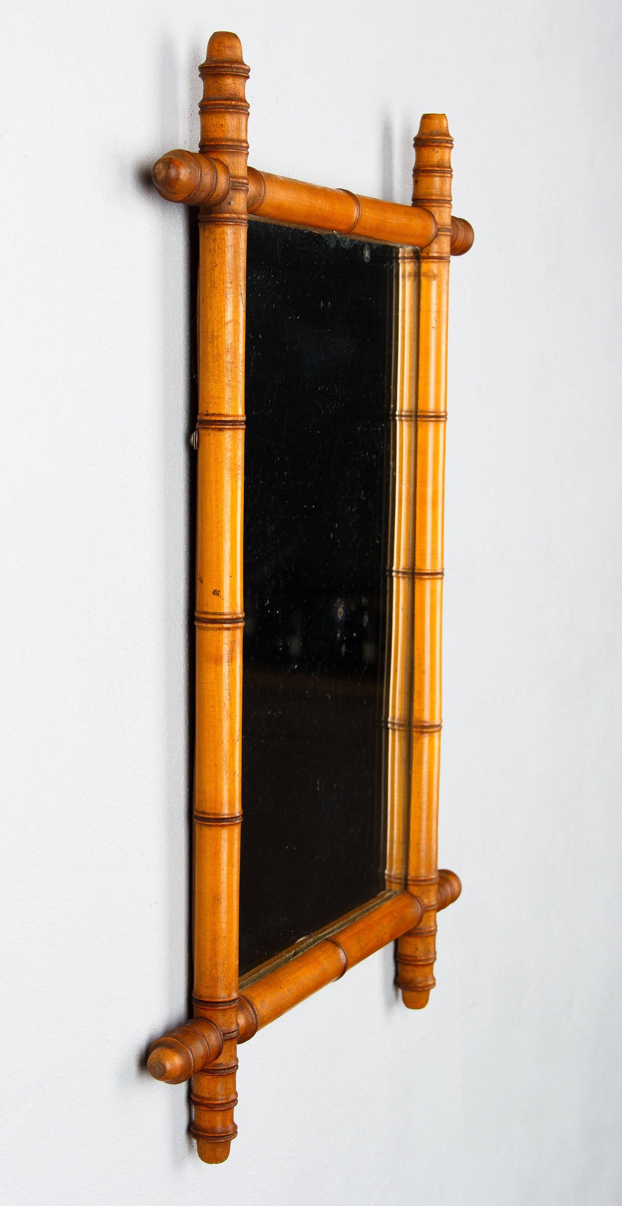 An early 1900s French Colonial style Mirror with a faux-bamboo frame made of beech wood.