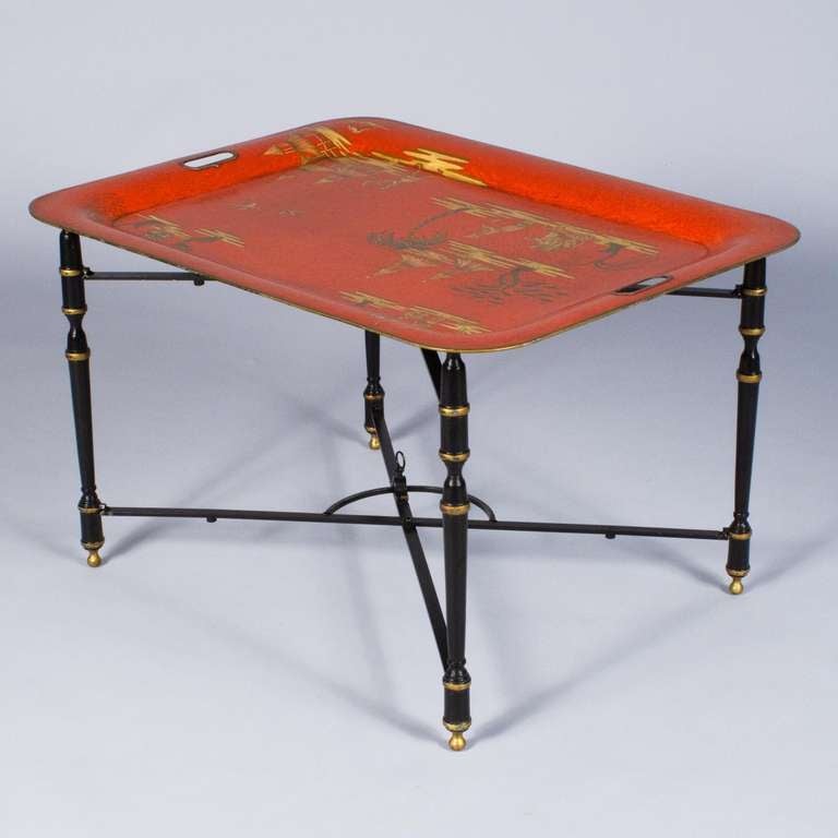 A colorful Tole Tray Tea Table in the Napoleon III Style with a black metal base with gold trims. The red tray has gilded chinoiserie motifs and is removable from base. The base has a mechanism allowing it to be folded.