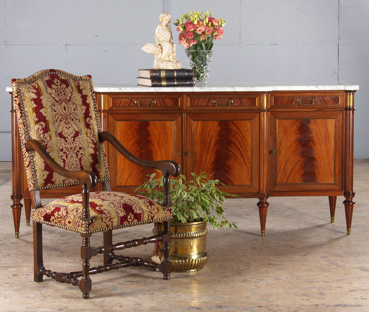 A magnificent four-door Louis XVI Style enfilade buffet made of flamed mahogany with a Carrara marble top. Featuring brass accents including trim around door panels and drawers, classic brass handles and striated plaques in the apron. The spindled