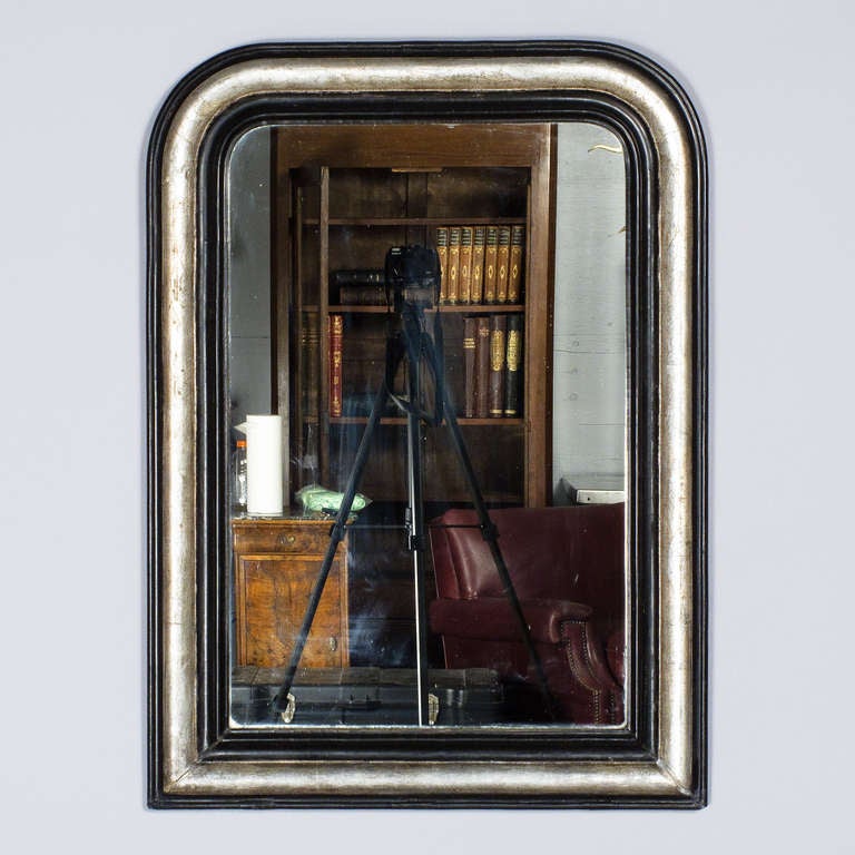 A Louis Philippe silver leaf mirror with its original glass. The frame features floral motifs and a painted black trim.