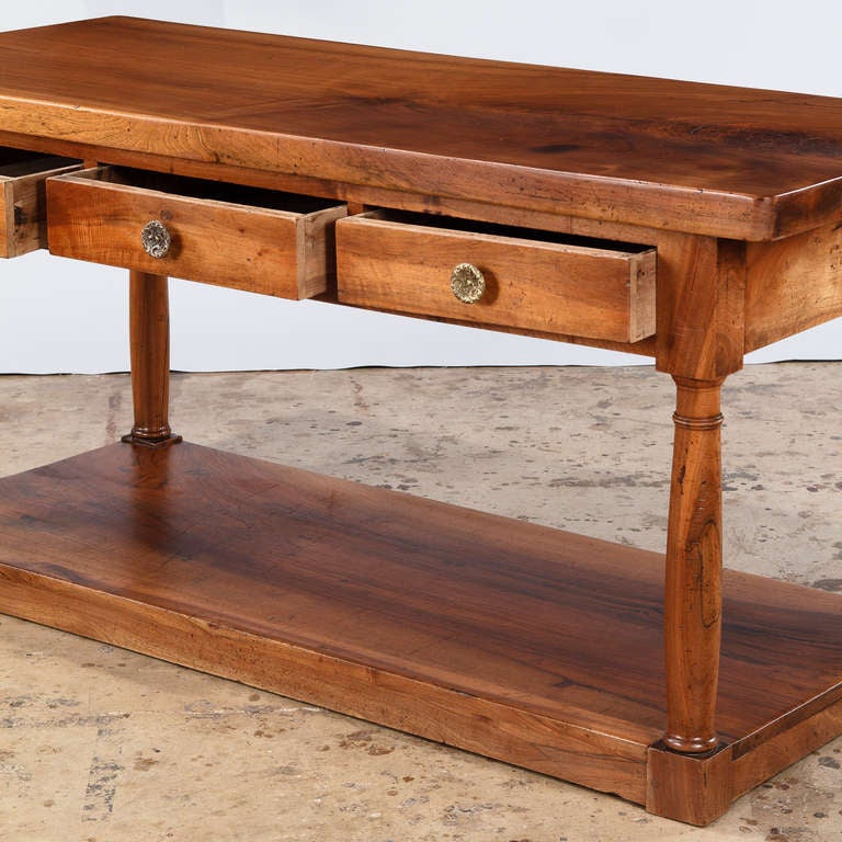 A fabulous Console Table from a silk factory in the Loire Region. Dating to the French Empire Period circa 1800's, this table is made of beautiful solid walnut. The console table features turned and tapered legs resting on a plinth base and 3