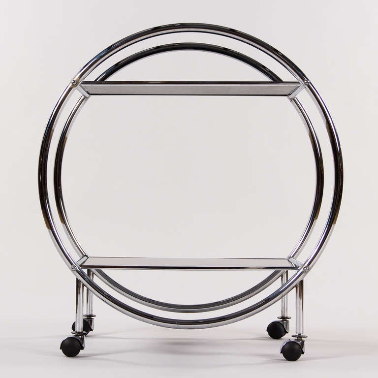 A vintage Italian bar cart in tubular chrome with two-mirrored smoked glass tops. The cart rolls easily on hard black plastic wheels. Very attractive 1970s design with a sleek and stylish round shape.