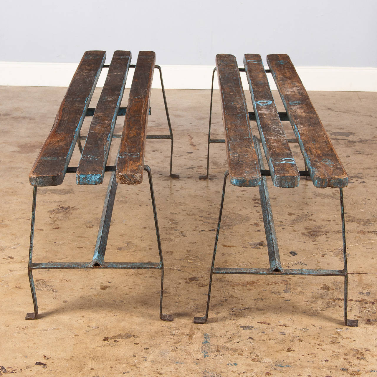 A pair of great looking vintage benches with an Industrial feel. They are made of three slats of pine on top and an iron base. The benches were originally painted in light blue but almost all the color is now gone.