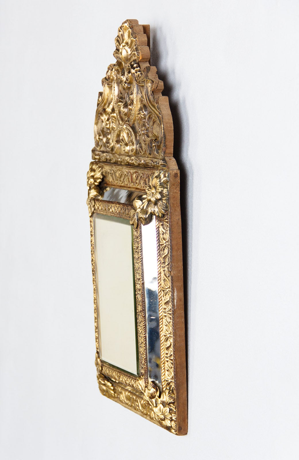 A small size Napoleon III period repousse mirror in gilded tin on a wooden back. The crest features a shell motif and the rest of the frame adorned with floral and foliate ornamentation. The mirrored glass is beveled. Size of glass is 12