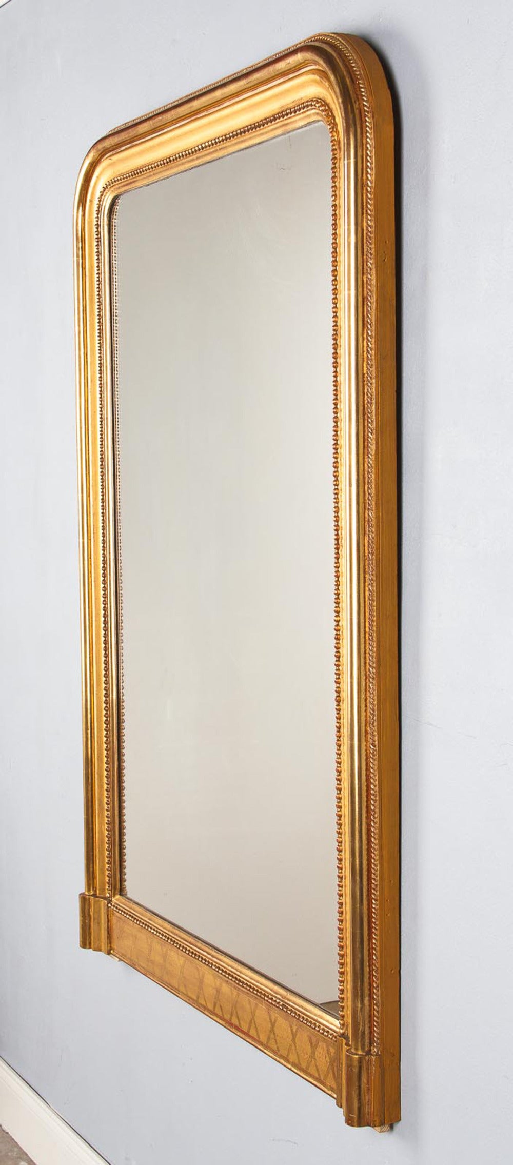 A substantial Louis Philippe period giltwood mirror with a triple molding on the frame, a beaded trim around the glass and a rope motif trim around the edge of frame. The base features cross shaped designs.