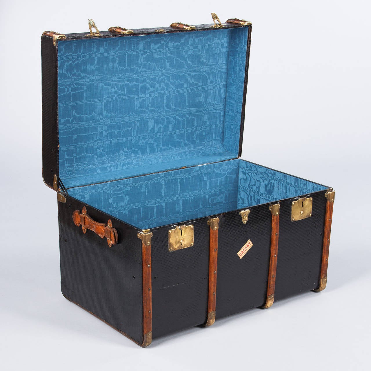 A wonderful traveling trunk from Lyon, France from the early 1900s. The trunk is made of poplar covered with black oil cloth. The lock plates are brass and the handles are made of leather. The trunk has a brass plaque on top with the original
