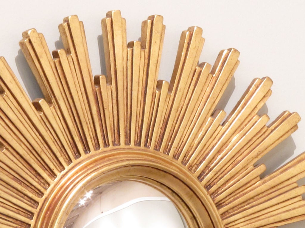 A very decorative Mid-Century Sunburst Mirror from Italy made of gilt wood with a convex glass.