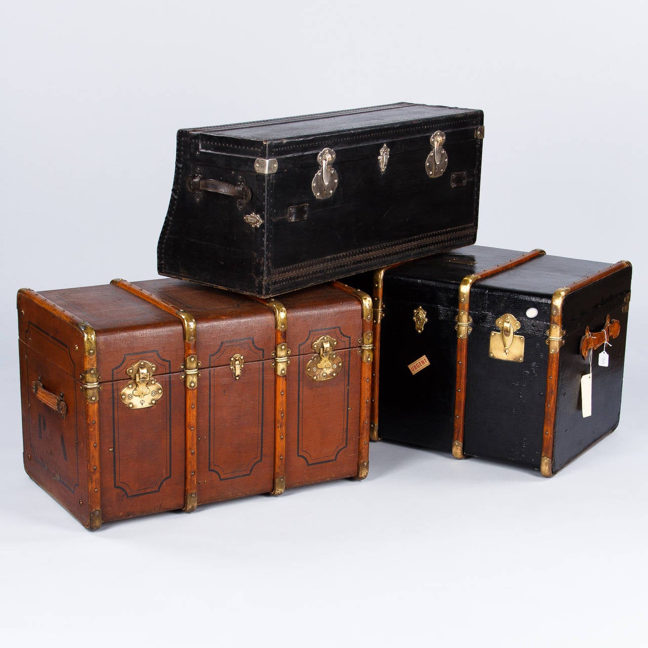 A very original old car trunk made of black leather with metal trim. The trunk opens up from the top and also the front with silver metal locks. The inside is painted wood in rust tones.