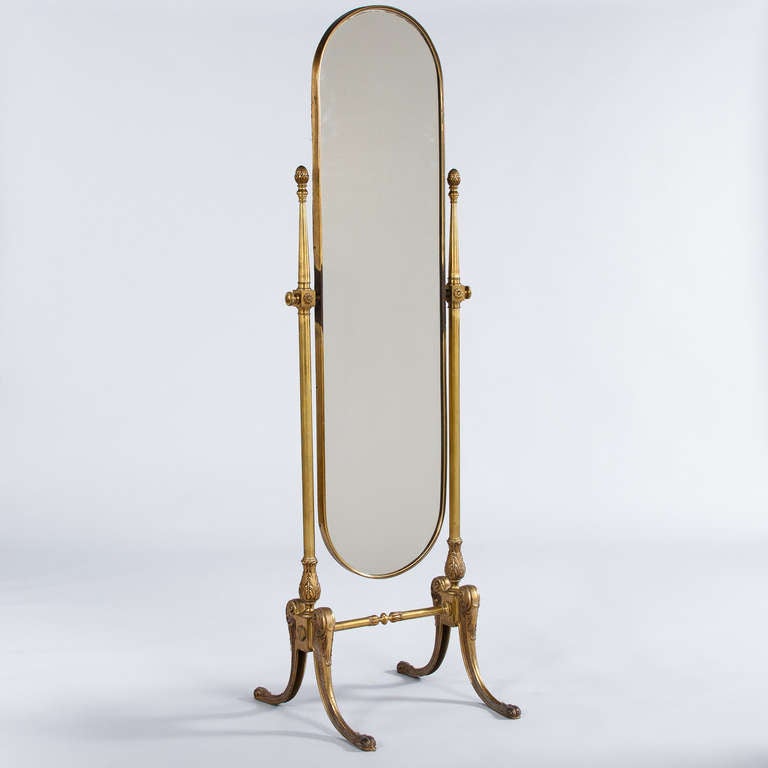 A Mid-century oval shaped Cheval Mirror on a brass stand with curved legs and acanthus leaves motifs. The Mirror itself tilts and measures 48.75