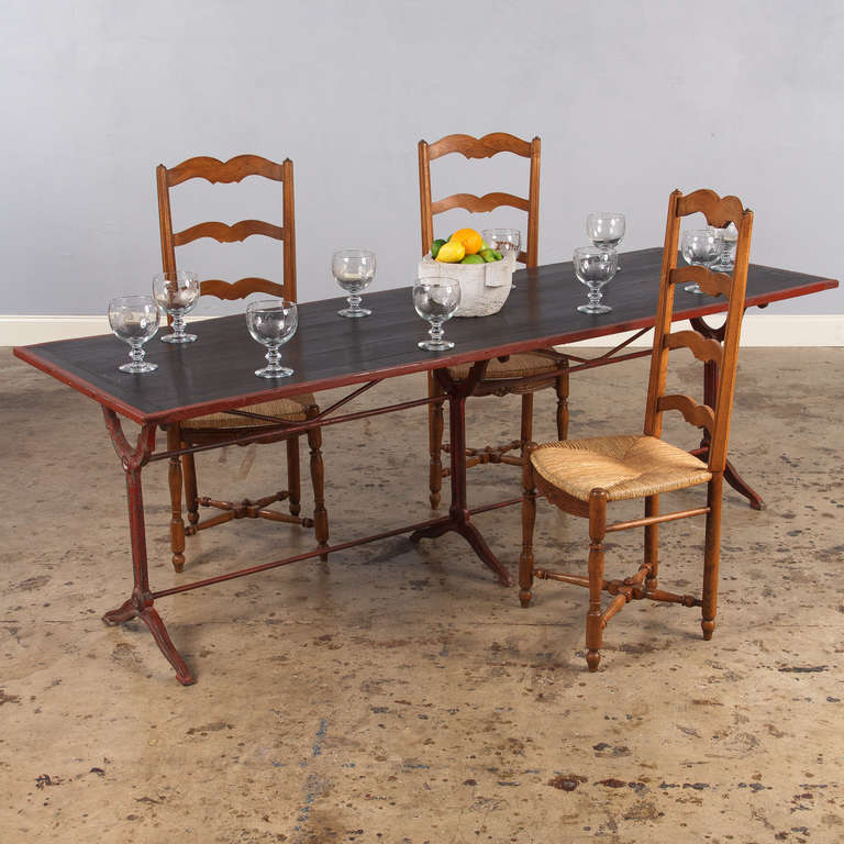 An irresistible bistro or restaurant table from Provence, circa 1920s. The long table has a sculpted forged iron six-legged base painted red and the pine top has been painted black with a red trim. The table can sit ten people. From floor to apron: