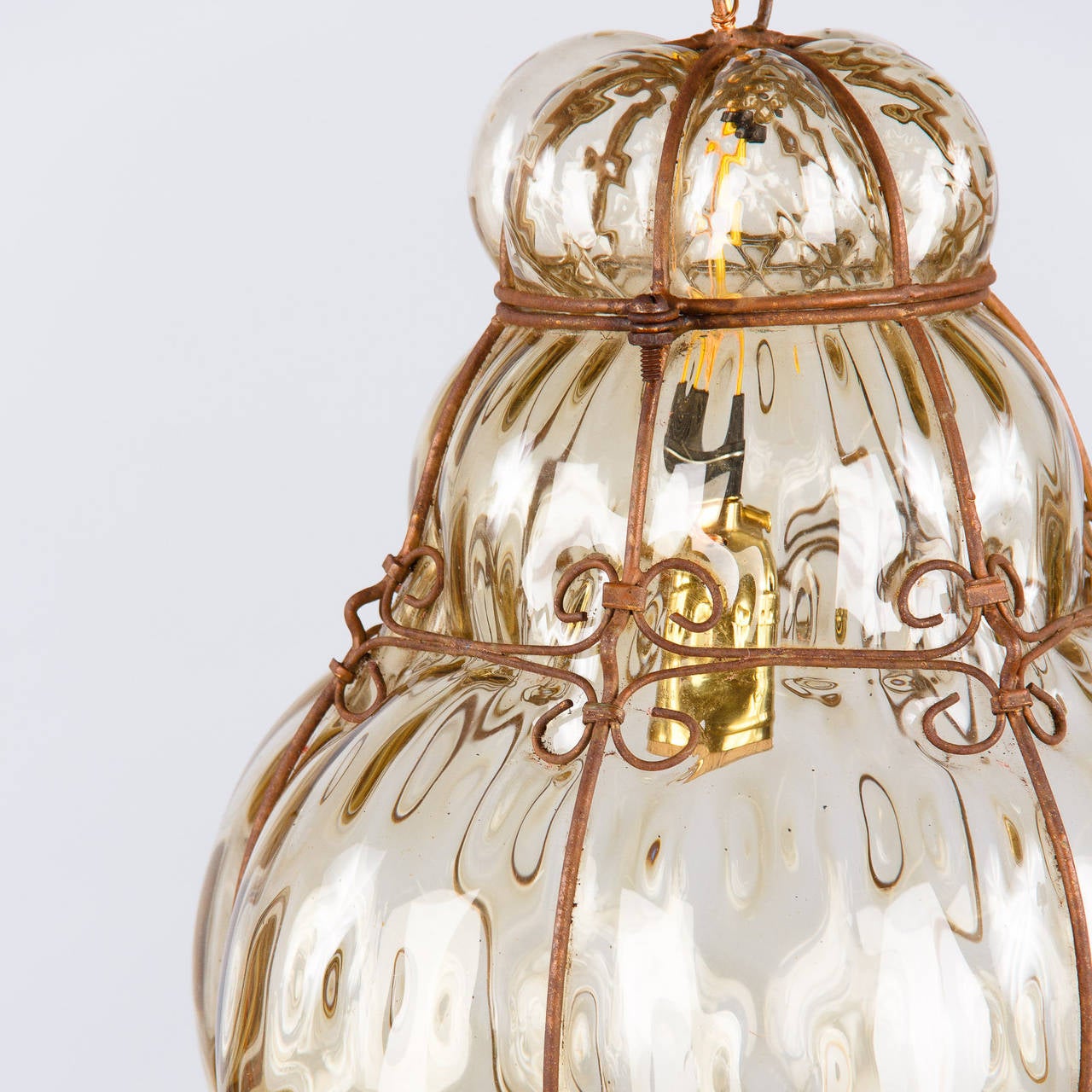 A 1940s Murano wire cage lantern with handblown bubble glass in light amber tones. The fixture is housing a single medium size light bulb up to 100w. The original adjustable chain and canopy add 24