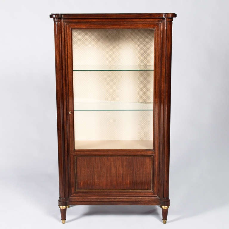 A Display Cabinet in the Louis XVI Style hand crafted in the city of Lyon by French designer Francisque Chaleyssin. The Vitrine is made of mahogany with a single glass door, glass sides and two glass shelves. The inside is lined with fabric. The