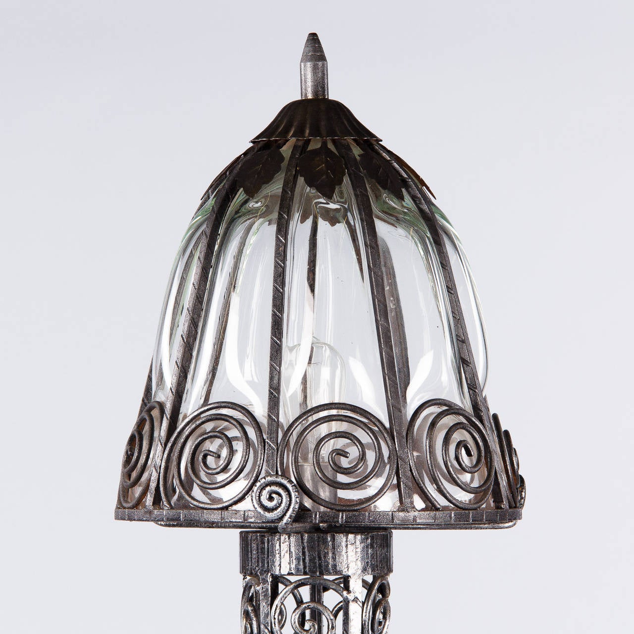 A wonderful floor lamp from the Art Deco period made of hammered forged iron with scroll design. The globe features handblown glass inside the iron and some grape leaf motifs. The lamp has been rewired with a single regular size light bulb up to 100