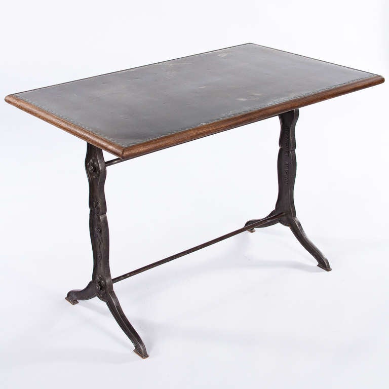 A great classic French Bistro Table with its forged iron base painted in black from the 1920's. Here, the usual marble top has been changed into a sheet of zinc with a trim in Brazilian walnut. The iron base has flower motifs and is signed Blanchet