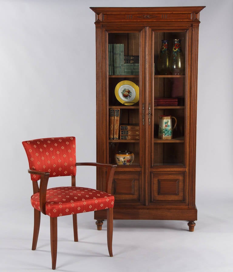 A delightful small size bookcase in the Louis XVI style from Lyon, circa 1900, made of cherrywood with beveled glass doors. The bookcase features raised panels at the bottom of doors, fluted sides and a simple diamond shaped carving with a rosette