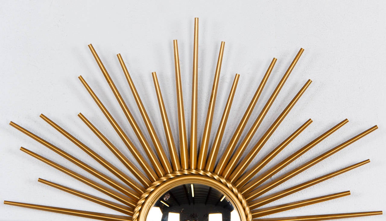 The sunburst mirror is an icon of the French design of the 1950s. The model created by Chaty-Vallauris is made of gilded metal and the glass is convex with a rope motif trim. The mirrored glass by itself measures 5.50